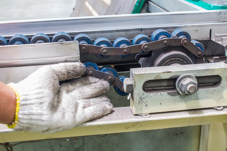 mechanik sprawdza stan taśmy przenośnika